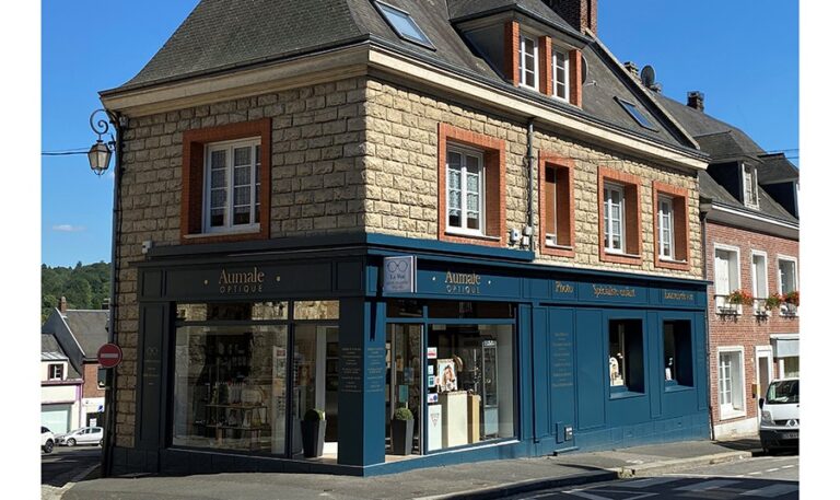 Bâtiment en pierre avec un commerce qui a une façade bleue