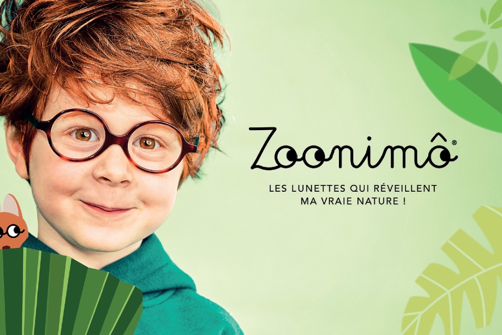portrait garçon souriant portant des lunettes ave un fond vert et le logo Zoonimo